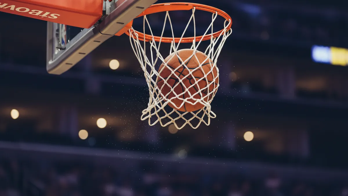 Balón de baloncesto NBA cayendo por la red, un encuadre cerrado.