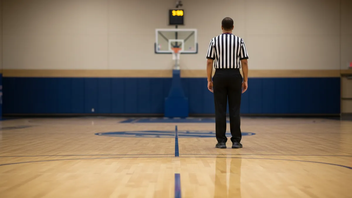 Un árbitro de la NBA en la cancha de baloncesto, visto desde atrás.