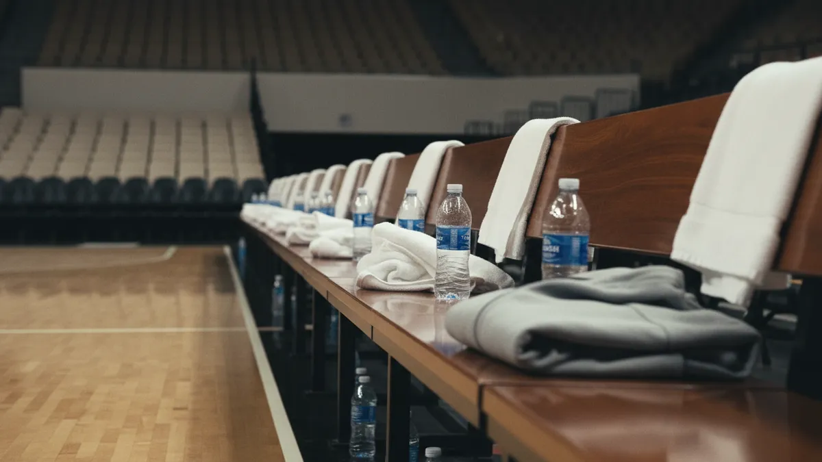 Banco del equipo de la NBA con toallas, botellas de agua y una chaqueta.